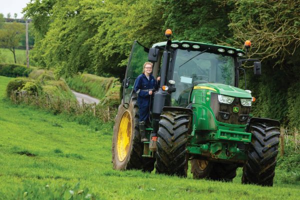 Young female agriculture student climbing into a tractor