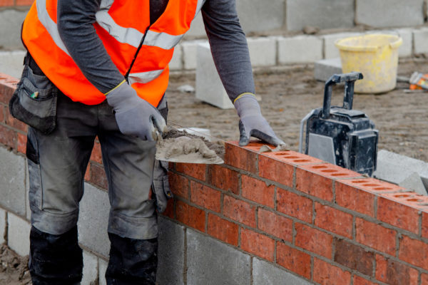 A bricklayer adding cement to a wall