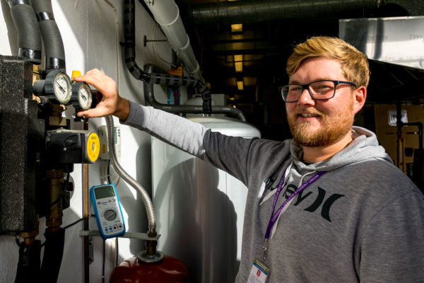 A plumbing student checking dials and a gauge